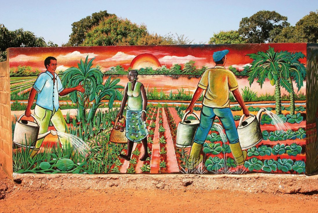 Bunte Wandmalerei in Burkina Faso, die Feldarbeiter:innen zeigt