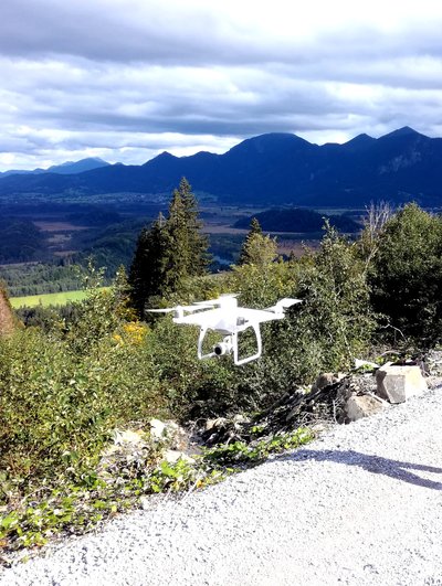 kleine weiße Drohne vor einer Gebirgslandschaft