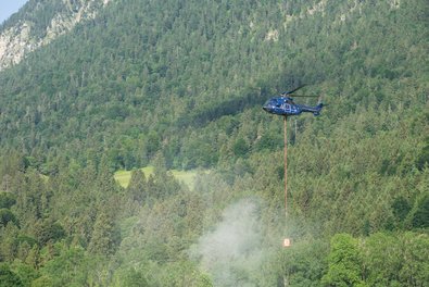  Helicopter with fire water tank flies over the forest