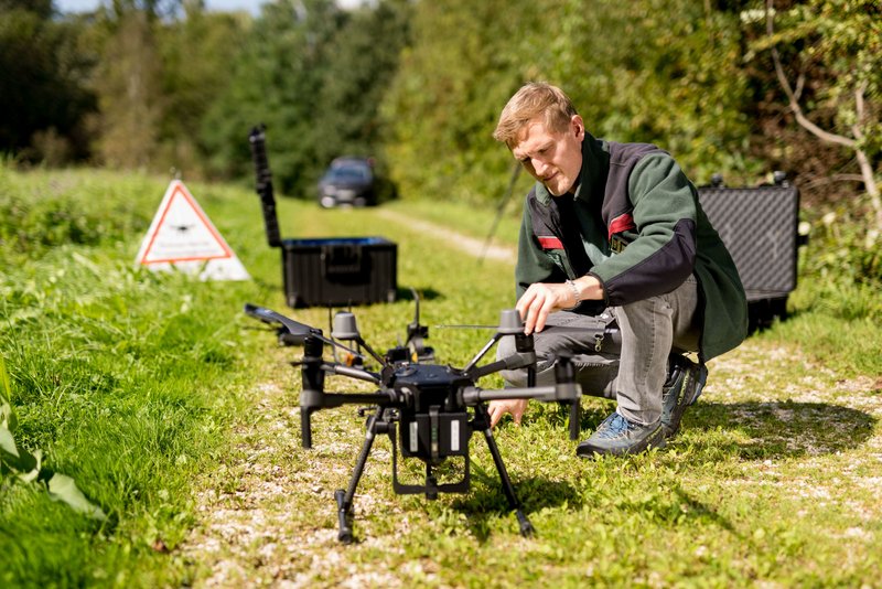 Mann startet eine Drohne von einem Waldweg