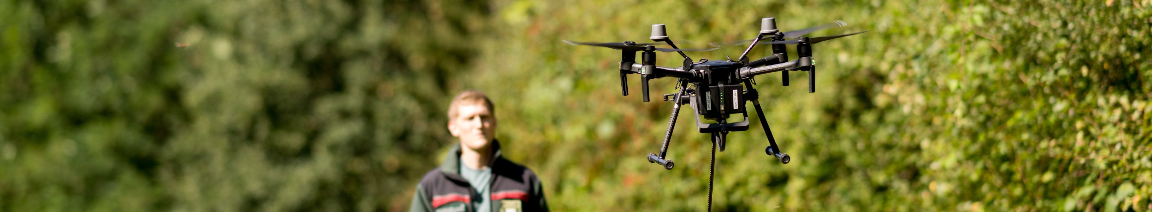 Mann startet eine Drohne von einem Waldweg